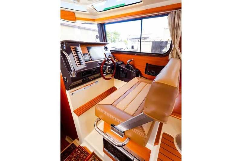 Slide: The Image of 2023 Ranger Tugs R-27 helm with leather seat, modern controls, and wood accents. - 27