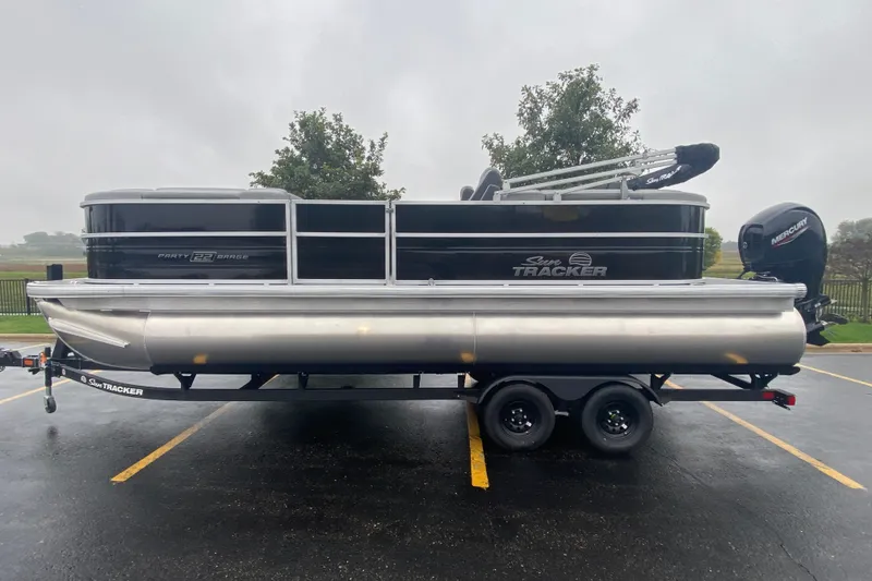 The Image of 2027 Sun Tracker Party Barge 22 DLX pontoon boat on trailer in parking lot. - 0