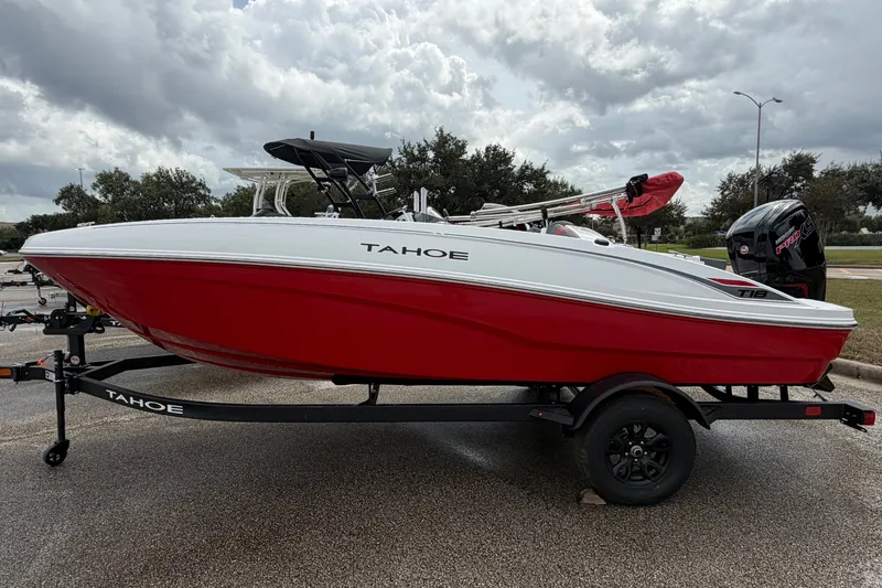 Slide: The Image of 2027 Tahoe T18 boat with red hull on trailer, parked outdoors under cloudy sky. - 3