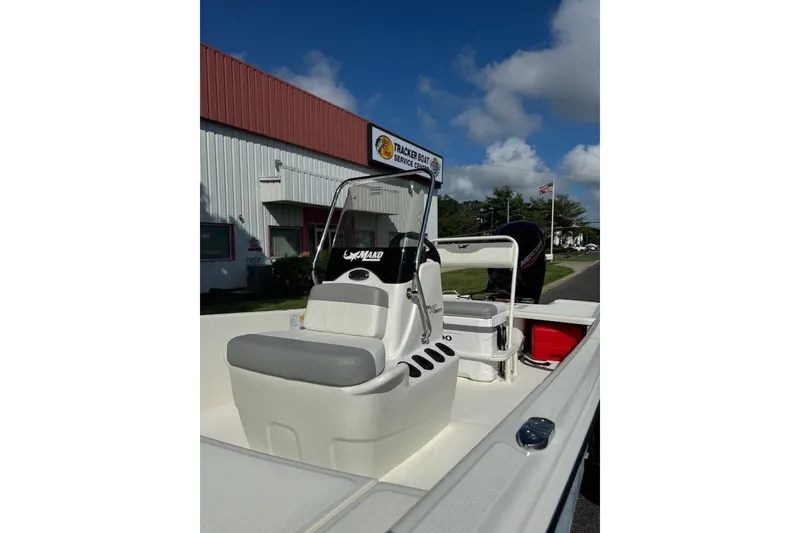 Slide: The Image of 2027 Mako Pro Skiff 17 CC boat with seating, parked near a service center. - 7