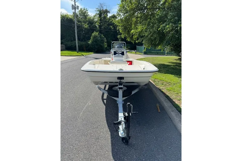 Slide: The Image of 2027 Mako Pro Skiff 17 CC boat on trailer, parked on a suburban street. - 2