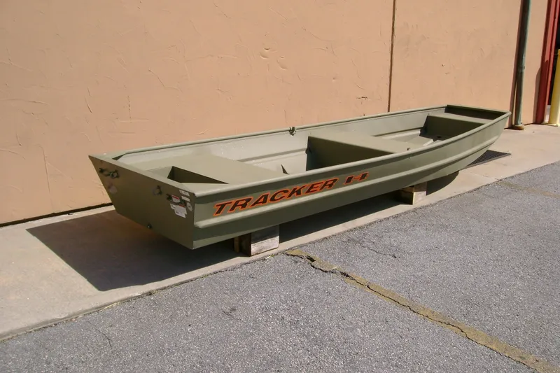The Image of 2027 Tracker Grizzly 14 Jon boat in olive green, displayed outdoors on wooden blocks. - 0