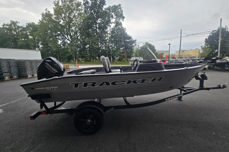 The Image of 2027 Tracker Pro Guide V-16 SC boat on trailer, parked outdoors. - 0