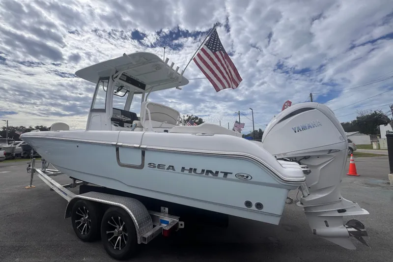Slide: The Image of 2024 Sea Hunt Escape 25 boat on trailer with American flag and Yamaha engine. - 9