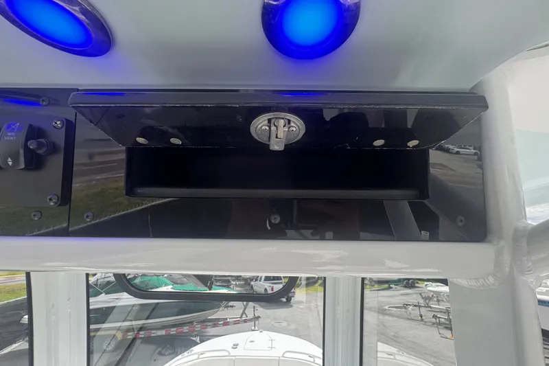 Slide: The Image of 2024 Sea Hunt Escape 25 boat dashboard with blue LED lights and storage compartment. - 39