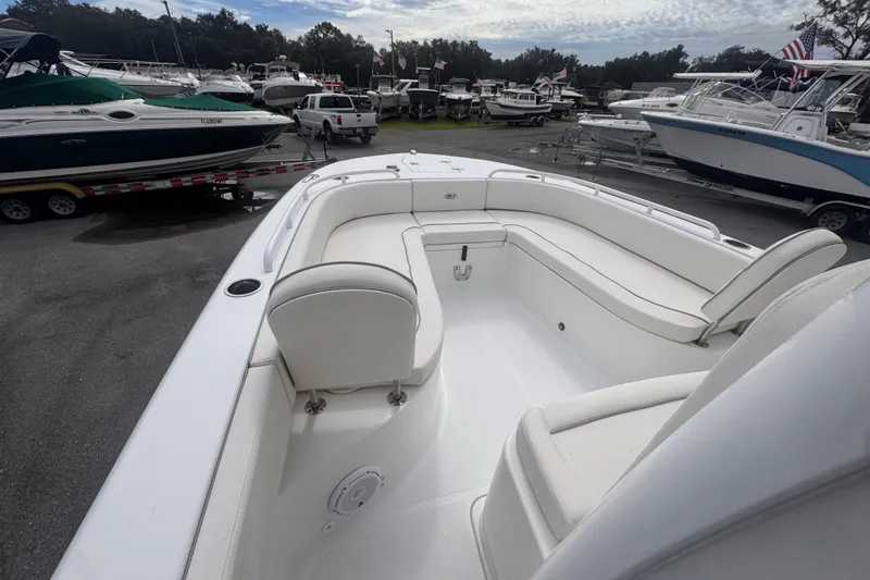 Slide: The Image of 2024 Sea Hunt Escape 25 boat with spacious white seating, parked among other boats. - 48