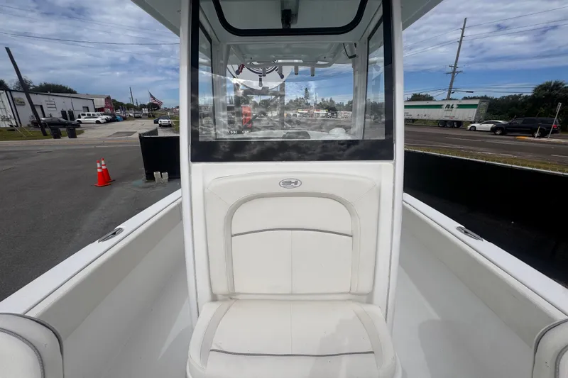 Slide: The Image of 2024 Sea Hunt Escape 25 boat with white seating and center console, parked outdoors. - 60