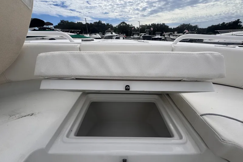 Slide: The Image of 2024 Sea Hunt Escape 25 boat storage compartment with cushioned seating, docked under cloudy sky. - 51