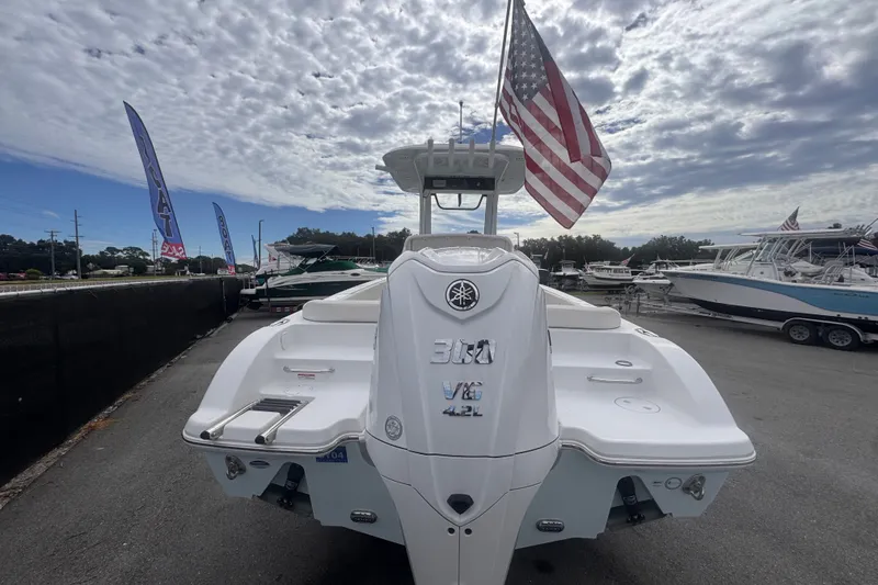 Slide: The Image of 2024 Sea Hunt Escape 25 boat with Yamaha engine, American flag, and cloudy sky backdrop. - 5
