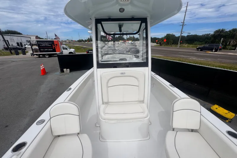 Slide: The Image of 2024 Sea Hunt Escape 25 boat interior with white seating, parked near a road. - 59