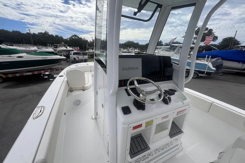 Slide: The Image of 2024 Sea Hunt Escape 25 boat with Garmin navigation, docked among other boats under a cloudy sky. - 22
