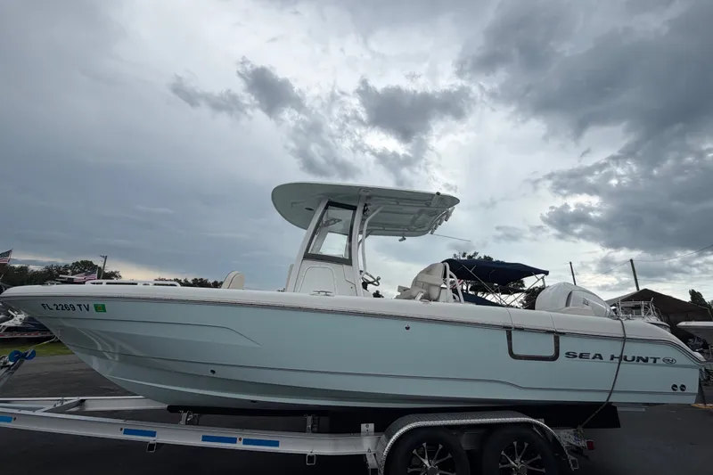 Slide: The Image of 2024 Sea Hunt Escape 25 boat on trailer under cloudy sky. - 2