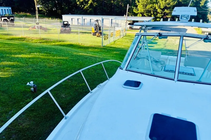 Slide: The Image of 2002 Pursuit 3000 Express boat docked on grassy area near fenced storage facility. - 65