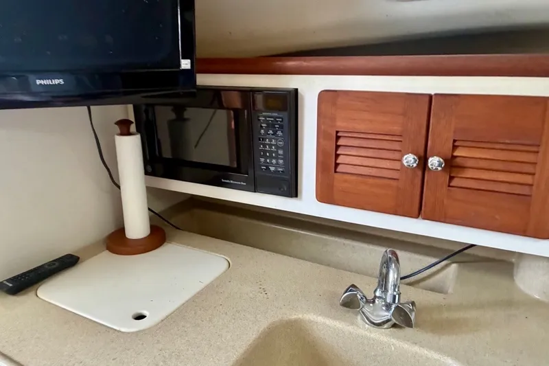 Slide: The Image of 2002 Pursuit 3000 Express boat interior with microwave, TV, wooden cabinets, and sink. - 45