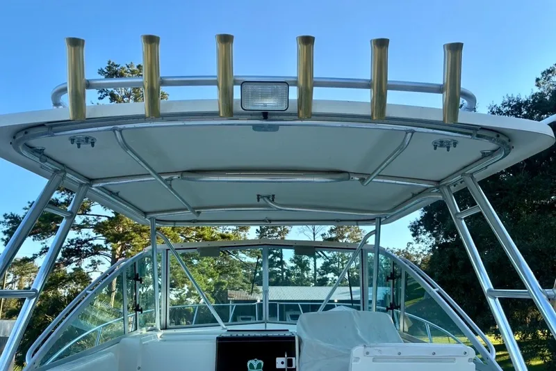 Slide: The Image of 2002 Pursuit 3000 Express boat with rod holders and canopy, set against a clear sky. - 29