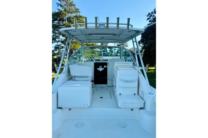 Slide: The Image of 2002 Pursuit 3000 Express boat interior with seating and helm, surrounded by trees. - 19