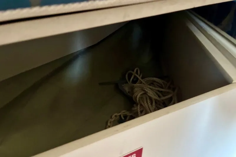 Slide: The Image of Open storage compartment with rope inside on a 2002 Pursuit 3000 Express boat. - 47