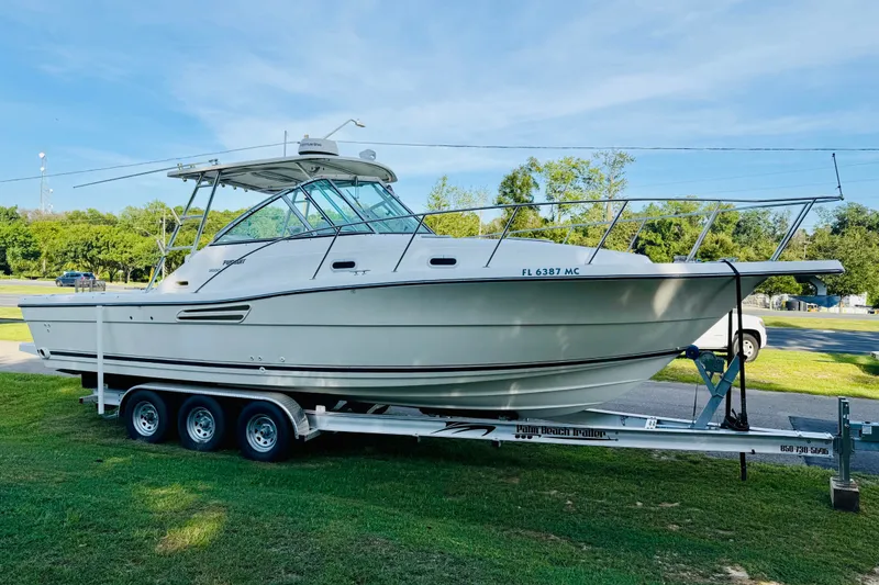 Slide: The Image of 2002 Pursuit 3000 Express boat on trailer, parked on grass under clear sky. - 4
