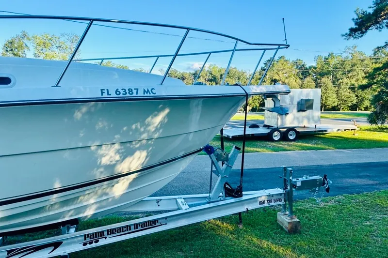 Slide: The Image of 2002 Pursuit 3000 Express boat on trailer, parked on grass with trees in background. - 90