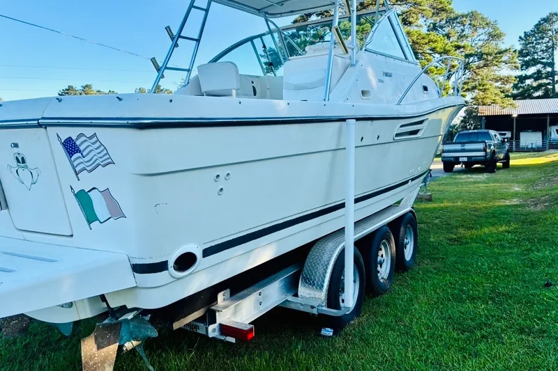 Slide: The Image of 2002 Pursuit 3000 Express boat on trailer, parked on grass with trees in background. - 85