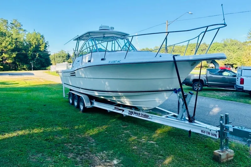 Slide: The Image of 2002 Pursuit 3000 Express boat on trailer, parked on grass, sunny day. - 16