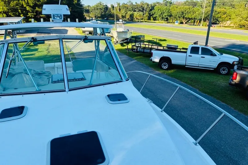 Slide: The Image of 2002 Pursuit 3000 Express boat docked near parked trucks and road. - 66
