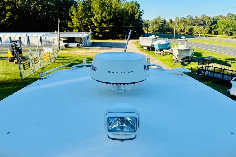 Slide: The Image of 2002 Pursuit 3000 Express boat with radar and spotlight, parked near other boats and a road. - 67