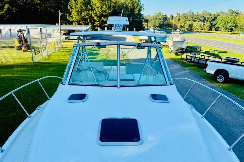 Slide: The Image of 2002 Pursuit 3000 Express boat on display, surrounded by greenery and parked vehicles. - 64
