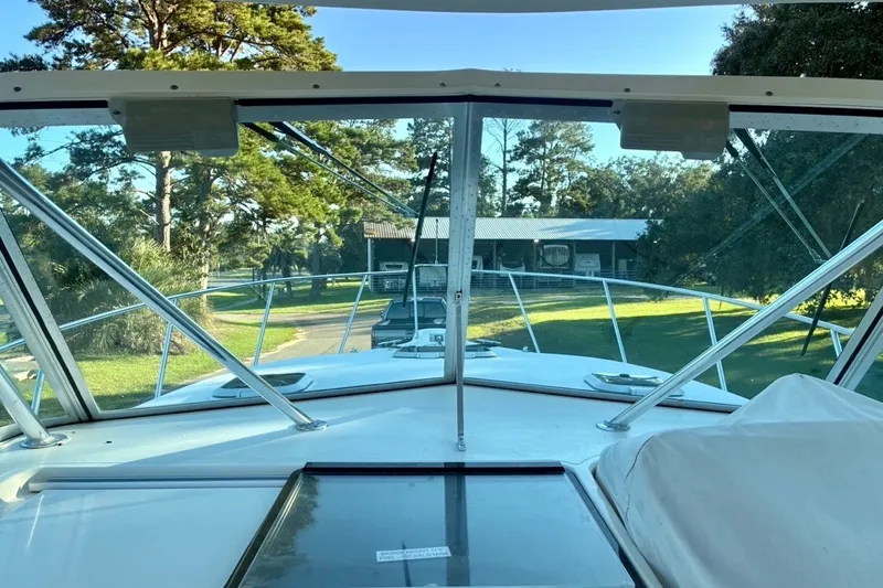 Slide: The Image of 2002 Pursuit 3000 Express boat view from cockpit, surrounded by trees and a building. - 28