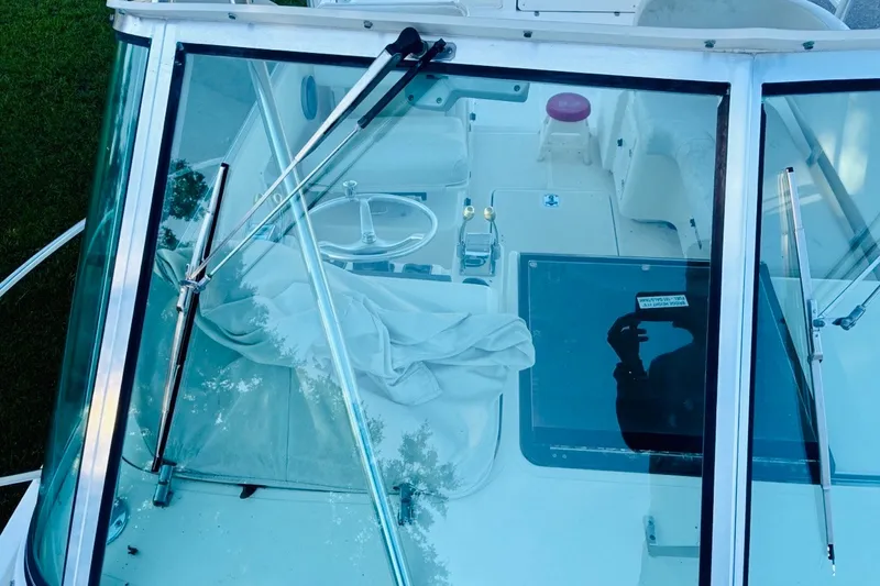 Slide: The Image of 2002 Pursuit 3000 Express boat cockpit view through windshield, showcasing steering and controls. - 68