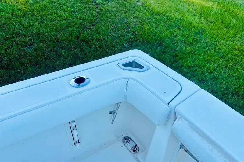 Slide: The Image of 2002 Pursuit 3000 Express boat interior with rod holder and storage, set against grassy background. - 80