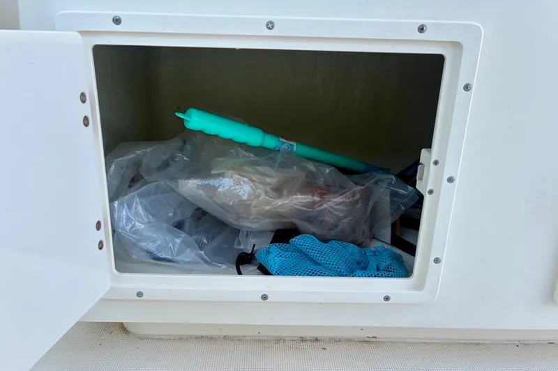 Slide: The Image of Storage compartment on a 2002 Pursuit 3000 Express boat with various items inside. - 31