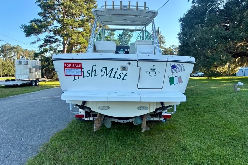 Slide: The Image of 2002 Pursuit 3000 Express boat for sale, parked on grass with flags and decals. - 17