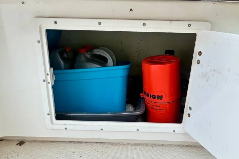 Slide: The Image of Storage compartment on a 2002 Pursuit 3000 Express boat with safety and maintenance supplies. - 32