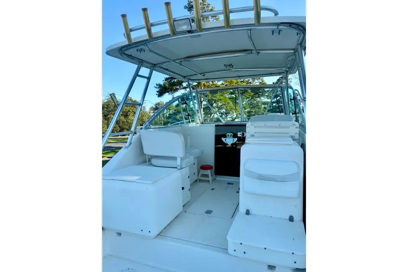 Slide: The Image of 2002 Pursuit 3000 Express boat interior with seating and helm, surrounded by trees. - 20