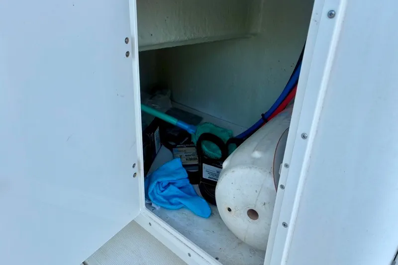 Slide: The Image of Storage compartment on a 2002 Pursuit 3000 Express boat with cleaning supplies and equipment. - 30