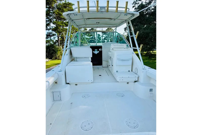 Slide: The Image of 2002 Pursuit 3000 Express boat interior with seating and helm, surrounded by trees. - 5