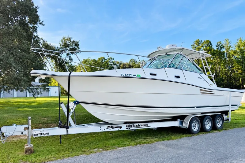 Slide: The Image of 2002 Pursuit 3000 Express boat on trailer, parked outdoors on a sunny day. - 2