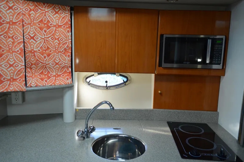 Slide: The Image of 2002 Formula 37 Performance Cruiser kitchen with sink, stove, microwave, and patterned curtains. - 40