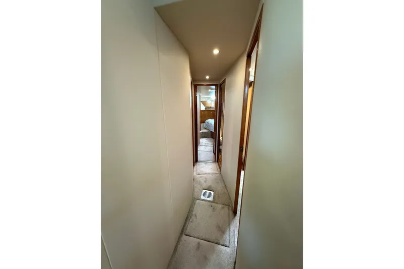 Slide: The Image of Narrow hallway inside 2002 Viking 52 Convertible yacht, featuring carpeted flooring and wooden doors. - 27