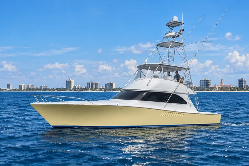 Slide: The Image of 2002 Viking 52 Convertible yacht cruising on blue ocean with city skyline in background. - 0