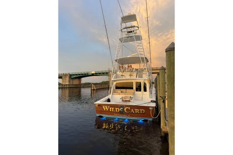 Slide: The Image of 2002 Viking 52 Convertible yacht docked at sunset near a bridge. - 2