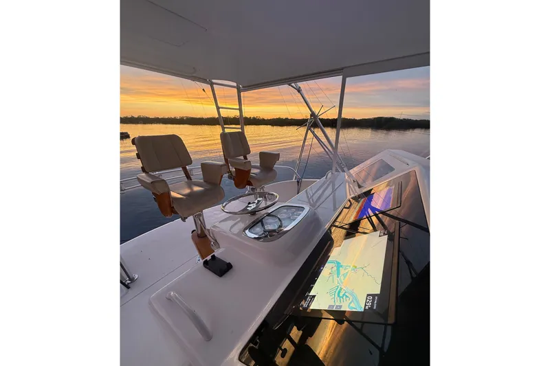 Slide: The Image of Cockpit view of 2002 Viking 52 Convertible yacht at sunset, featuring navigation screens and seating. - 10