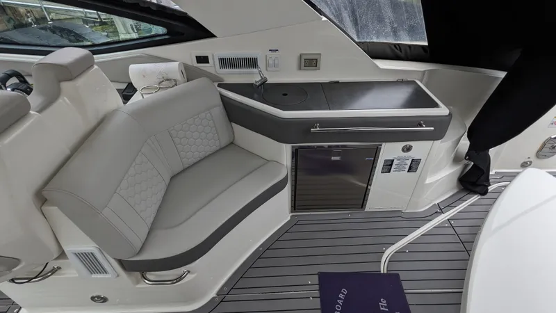 Slide: The Image of The image shows the interior of a 2021 Sea Ray Sundancer 320 Outboard with gray seating and a small kitchenette. - 7