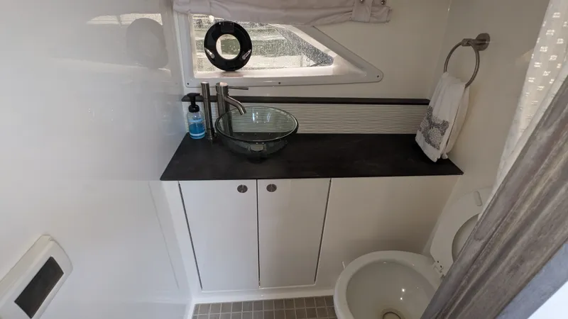 Slide: The Image of The image shows a modern boat bathroom with a sink, toilet, and window. - 24