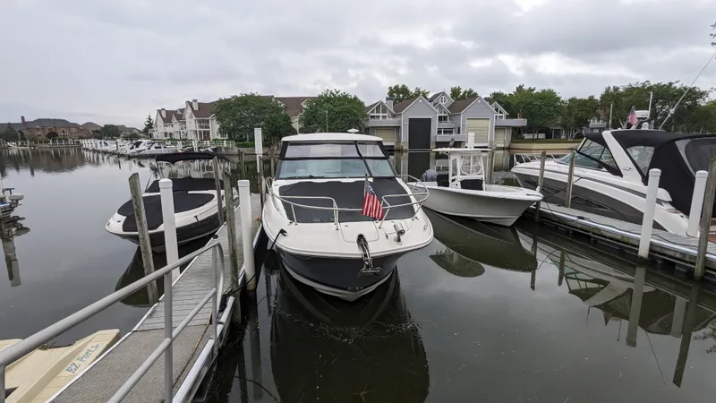 Slide: The Image of A 2021 Sea Ray Sundancer 320 Outboard docked in a calm marina, surrounded by other boats. - 1