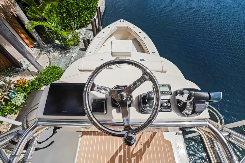 Slide: The Image of Helm of 2013 Bahama 41 boat overlooking water and lush greenery. - 42