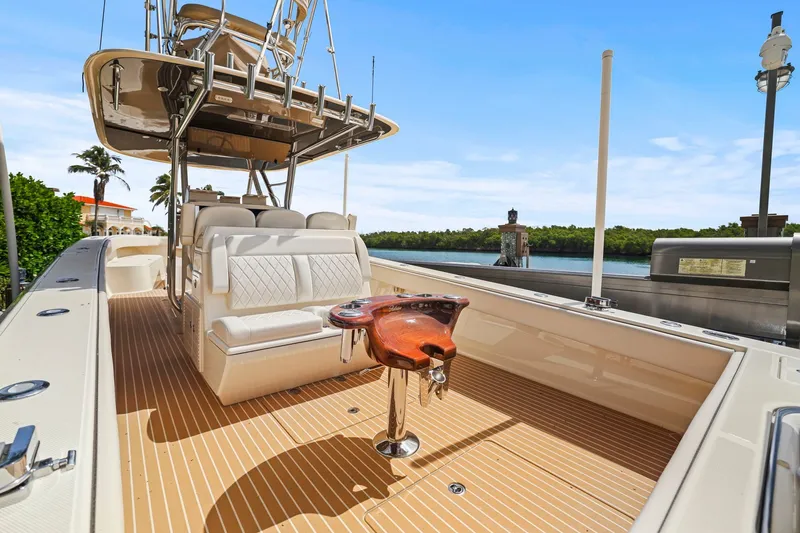 Slide: The Image of 2013 Bahama 41 boat interior with seating and fishing equipment, docked by a scenic waterfront. - 28