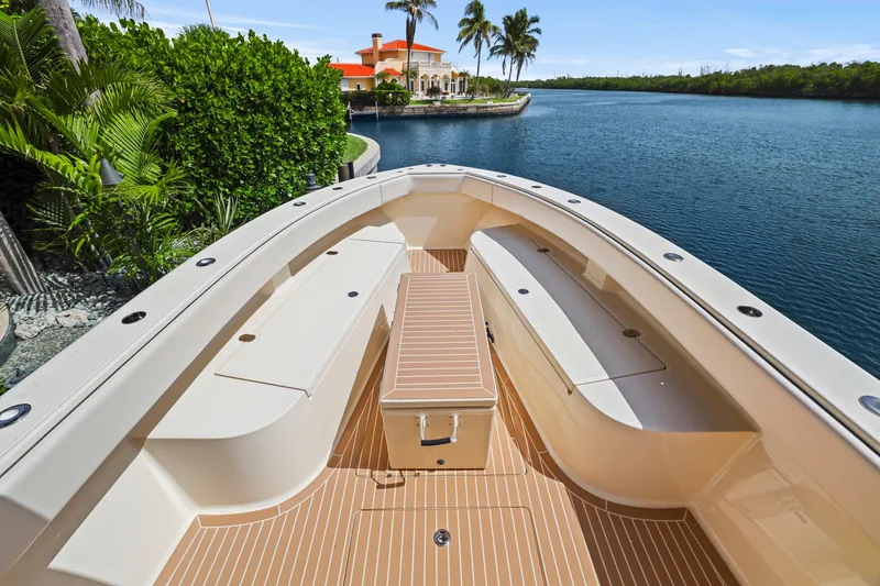 Slide: The Image of 2013 Bahama 41 boat deck with seating, docked near waterfront property and lush greenery. - 11