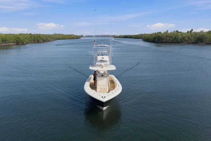 Slide: The Image of 2013 Bahama 41 boat cruising through a serene waterway surrounded by lush greenery. - 3